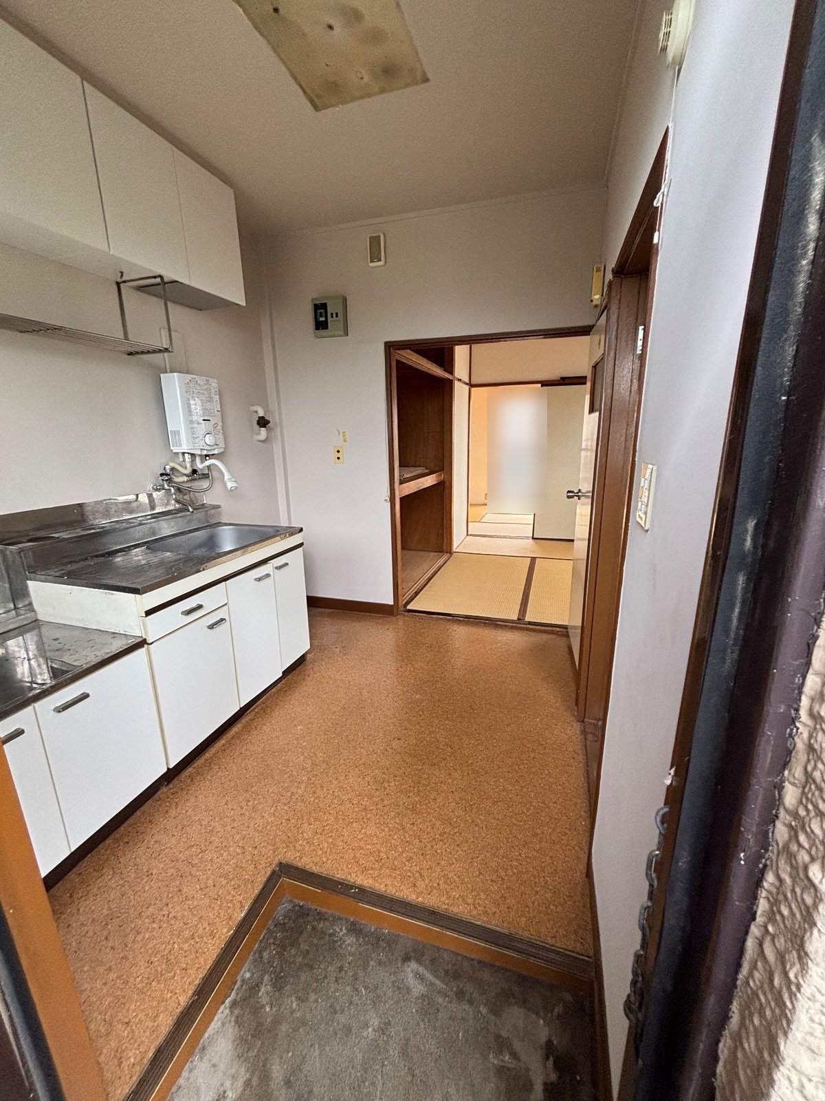 作業後の2階の別の住戸の台所。コルクの床に物は残っておらず、奥に畳の部屋が見える